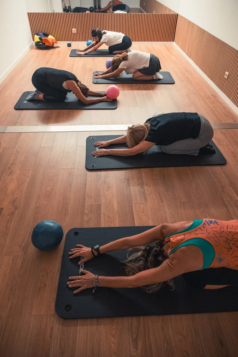 Aula de pilates no estúdio, com tapetes sobre o chão de madeira