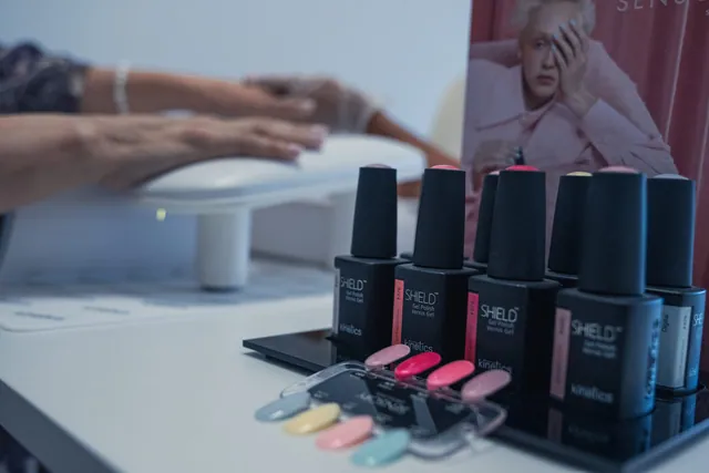Frascos de verniz de gel e amostras de cores, junto ao apoio de mãos da manicure