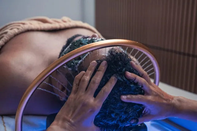 Ritual de Head Spa: cliente deitado, com máscara de pedras nos olhos e um arco dourado sobre a cabeça