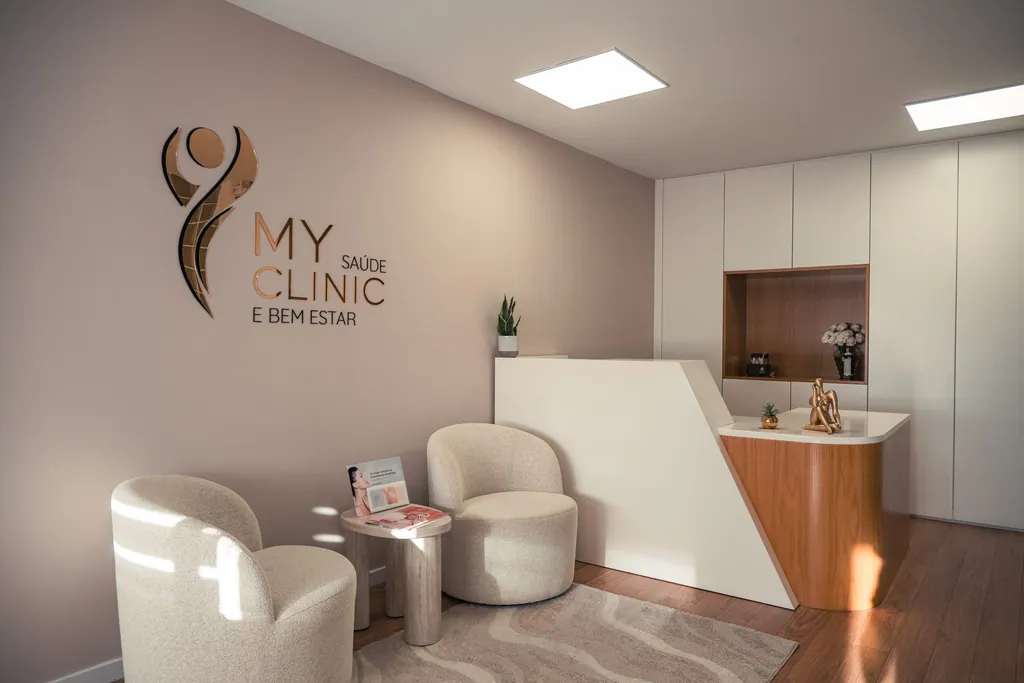 Receção da MyClinic, com o logótipo na parede, dois cadeirões e o balcão