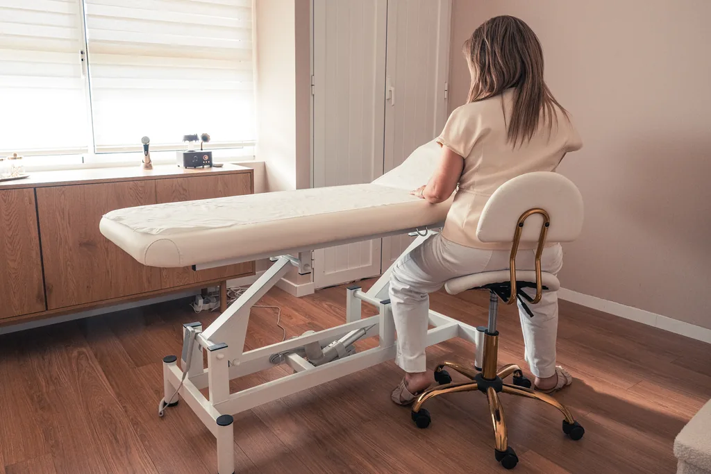 Sala de tratamentos, com a profissional sentada junto à marquesa